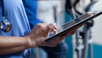 Close up of medical assistant touching tablet display